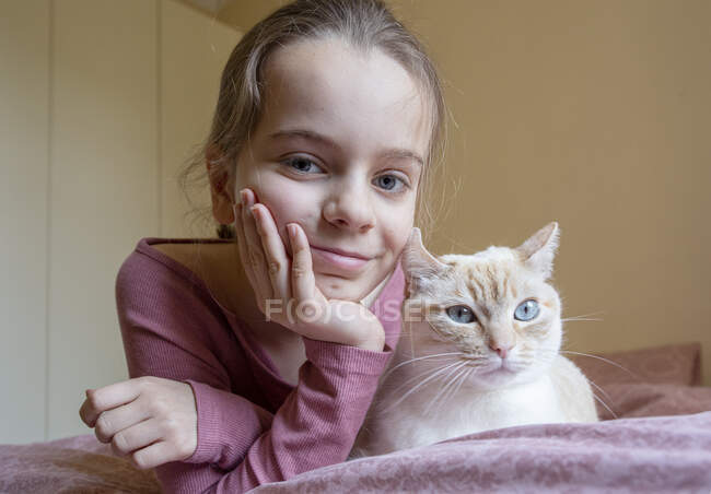 Portrait of girl and white and ginger cat lying on bed. — Stock Photo