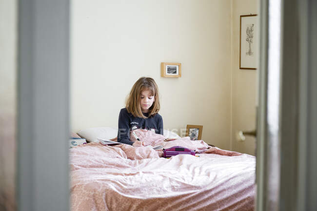 Menina sentada em sua cama em seu quarto, estudando, escola em casa com laptop e notebook — Fotografia de Stock