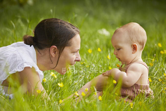Mãe e bebê filha brincando em um prado. — Fotografia de Stock