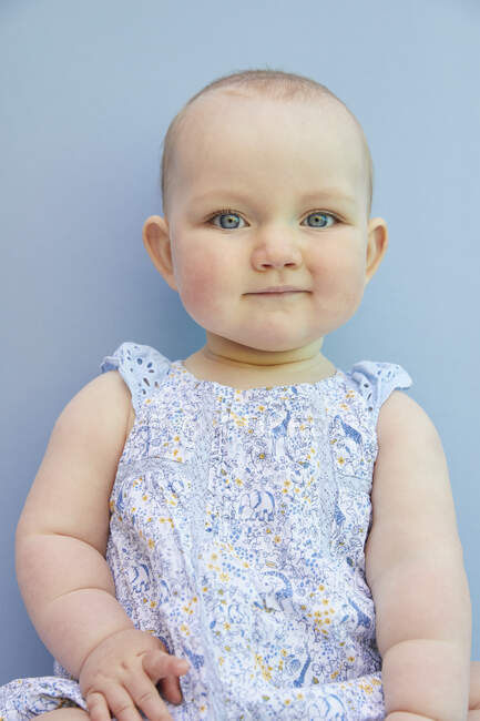 Portrait of baby girl on pale blue background. — Stock Photo