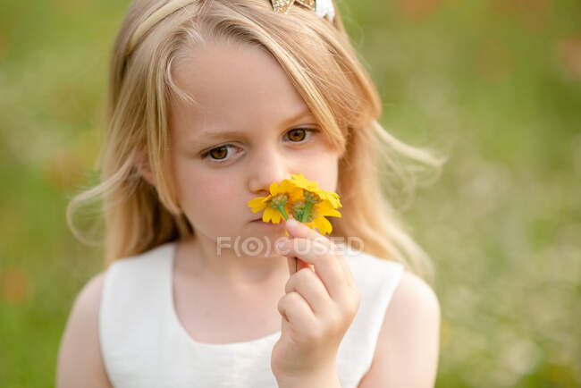 Ritratto di giovane ragazza con capelli biondi in un prato, che profuma di fiori selvatici gialli. — Foto stock