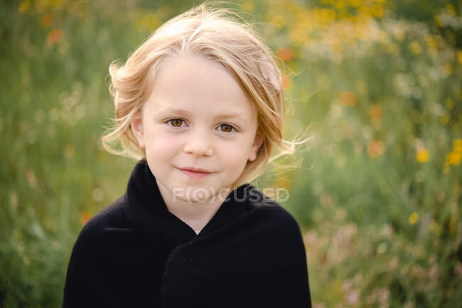 Portrait of young girl with blond hair in a meadow, looking at camera. — Stock Photo
