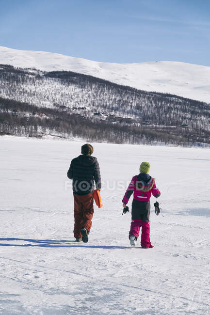 Rear view of two boys walking on frozen lake in Vasterbottens Lan, Sweden. — Stock Photo