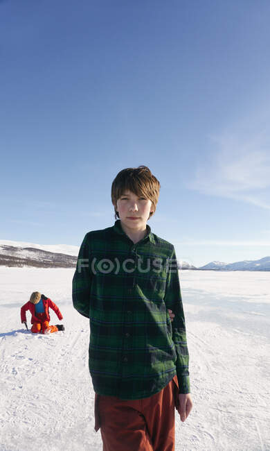Junge steht auf zugefrorenem See in Vasterbottens Lan, Schweden und blickt in die Kamera. — Stockfoto
