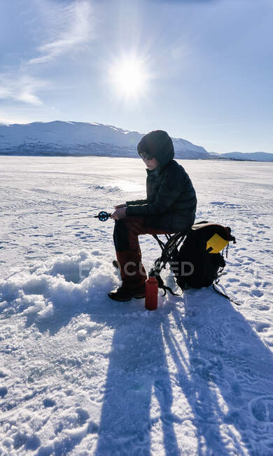 Boy ice-fishing on frozen lake in Vasterbottens Lan, Suécia. — Fotografia de Stock