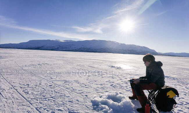 Boy ice-fishing on frozen lake in Vasterbottens Lan, Suécia. — Fotografia de Stock