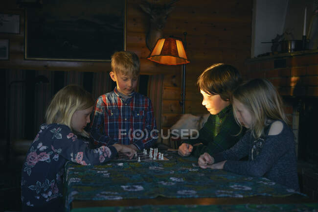 Група дітей сидить за столом у дерев'яній хатинці, граючи в шахи, Вастерботенс Лань, Швеція.. — стокове фото