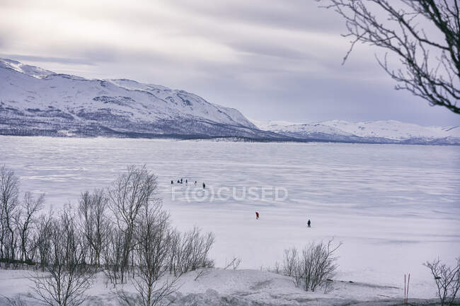 Vista sul lago ghiacciato con persone in lontananza, Vasterbottens Lan, Svezia. — Foto stock