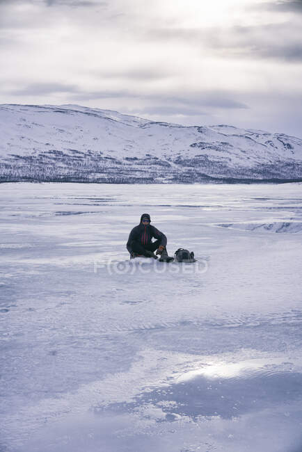 Man ice-fishing on frozen lake in Vasterbottens Lan, Suécia. — Fotografia de Stock