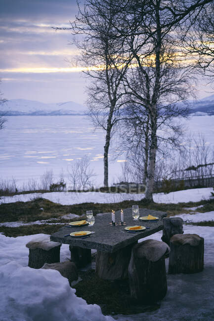 Set da tavola per esterni con piatti, bicchieri di vino e candele a Vasterbottens Lan, Svezia. — Foto stock