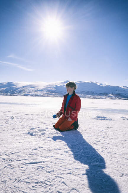 Boy kneeling on frozen lake in Vasterbottens Lan, Sweden. — Stock Photo