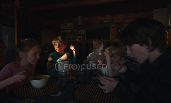 Група дітей сидить за столом у дерев'яній хатині, поїдаючи, Вастерботена Лана, Швеція.. — стокове фото