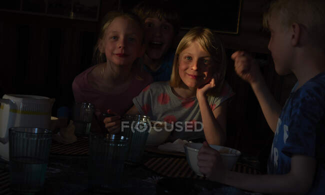 Garçon et deux filles assis à une table dans une cabane en rondins, manger, Vasterbottens Lan, Suède. — Photo de stock
