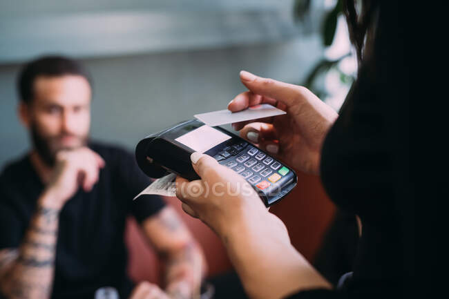 Close up of waitress in a bar, holding card reader and credit card. — Stock Photo
