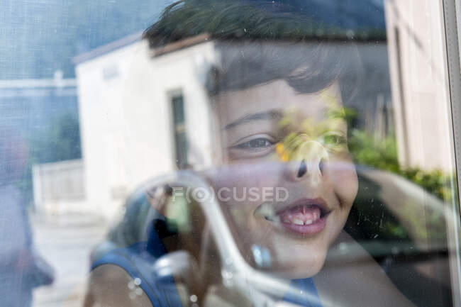 A young boy with his nose pressed against a glass window, indoors during lockdown. — Stock Photo
