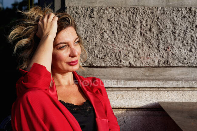Retrato de mulher de negócios bonita em casaco vermelho com cabelo loiro, ajustando o cabelo — Fotografia de Stock