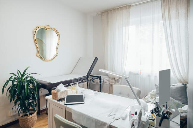 Vista interior de um salão de beleza, com mesa de tratamento e espelho de parede dourada. — Fotografia de Stock