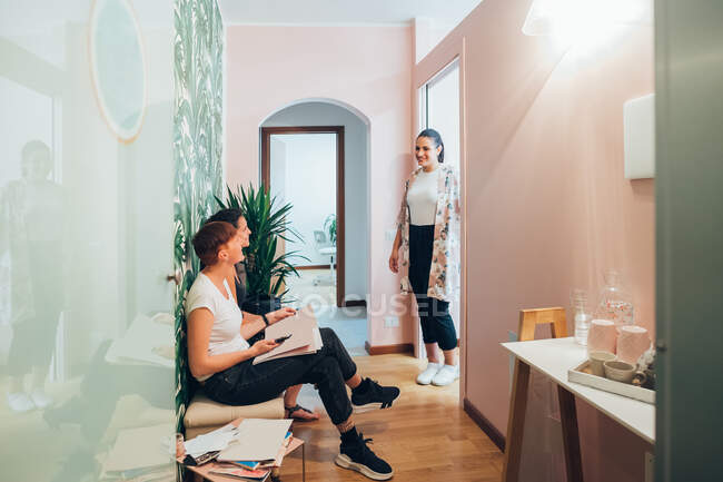 Beautician smiling at two women sitting in waiting room of beauty salon. — Stock Photo