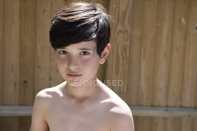 Portrait de garçon aux cheveux bruns dans un jardin en été, regardant la caméra. — Photo de stock