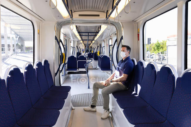 Man wearing face mask sitting in an empty train in Florence, Italy during the Corona virus crisis. — Stock Photo