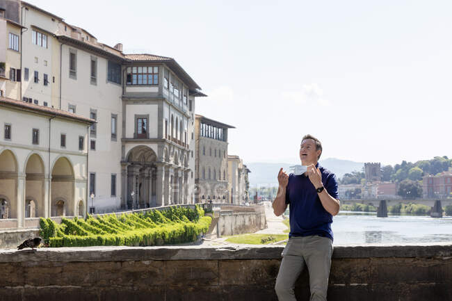 Mann mit Mundschutz steht während der Coronavirus-Krise allein auf Brücke über den Arno in Florenz, Italien. — Stockfoto