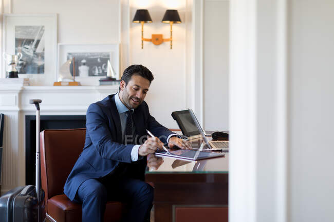 Homme d'affaires assis à une table, écrivant sur tablette numérique. — Photo de stock