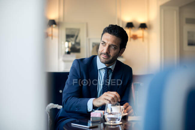 Бізнесмен сидить за столом, перемішуючи чашку кави . — стокове фото