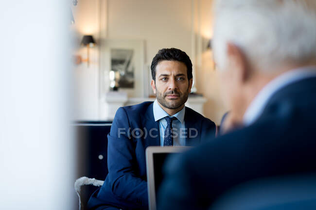 Два бізнесмени сидять в приміщенні, розмовляючи . — стокове фото