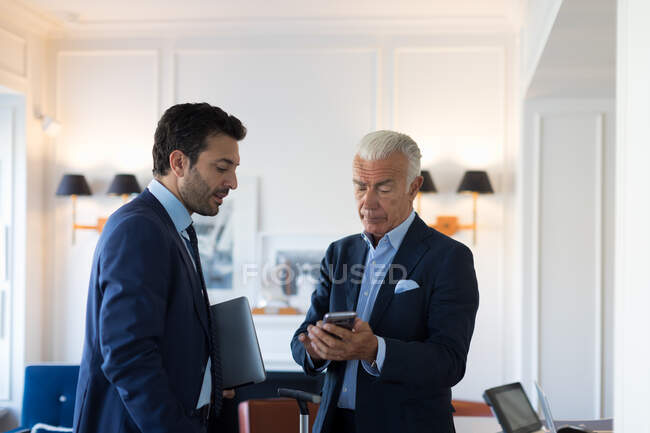 Two businessmen standing indoors, talking. — Stock Photo