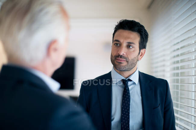 Два бізнесмени, що стоять в приміщенні, розмовляють . — стокове фото
