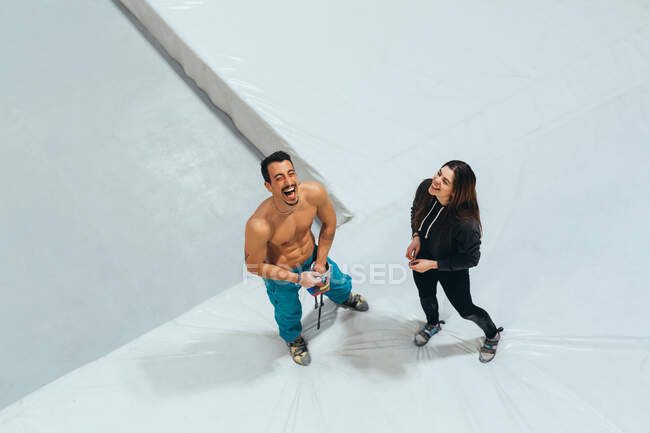 Vue grand angle de la femme et de l'homme debout devant le mur d'escalade intérieur. — Photo de stock