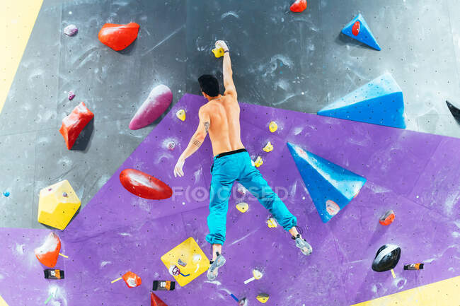 Rear view of man ascending rock climbing wall. — Stock Photo