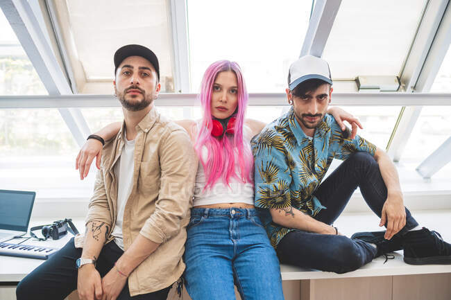 Portrait of young woman with long pink hair and two bearded young men wearing baseball caps — Stock Photo