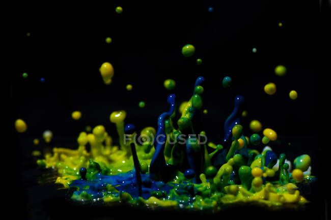 Escultura de pintura - Fotografía de alta velocidad de salpicaduras de pintura verde, amarilla y azul. - foto de stock