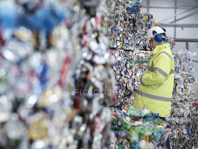 Worker inspecting mixed waste in waste recycling plant. — Stock Photo