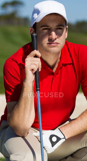 Portrait of male golfer wearing red shirt and white baseball cap and glove. — Stock Photo