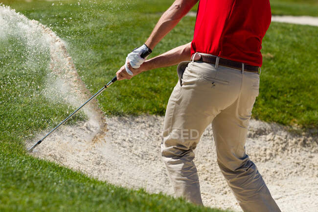 Golfista maschio scheggiando fuori trappola sabbia. — Foto stock