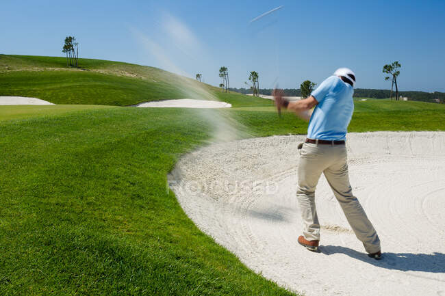 Male golfer chipping out of sand trap. — Stock Photo