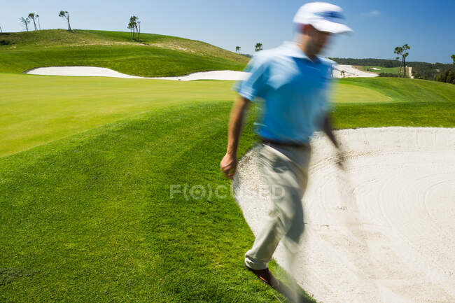Hombre golfista caminando en trampa de arena. - foto de stock