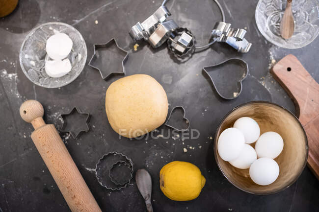 Alto ángulo de primer plano de pasta casera masa, huevos, cortadores de galletas y rodillo. - foto de stock