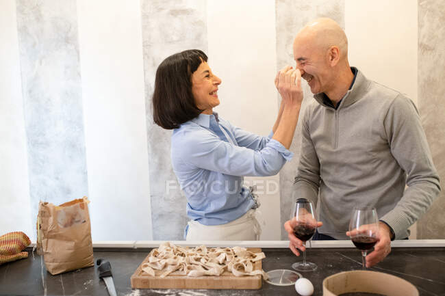 Couple debout dans une cuisine, faire des pâtes fraîches maison. — Photo de stock