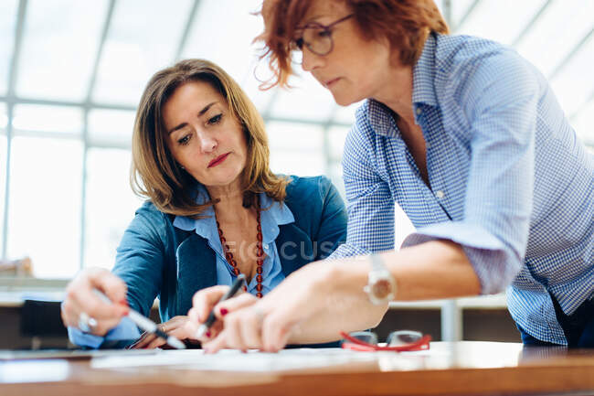Две женщины, сидящие за столом, решают проблемы — стоковое фото