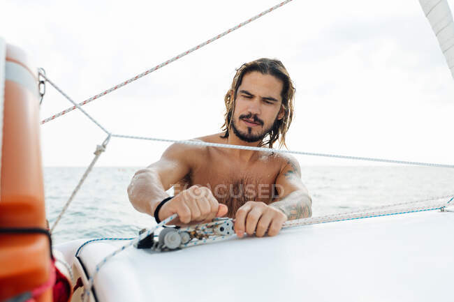 Чоловік готує вітрильник у морі — стокове фото