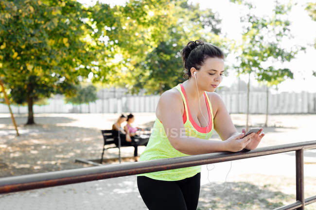 Woman using cellphone in park, friends taking break in background — Stock Photo