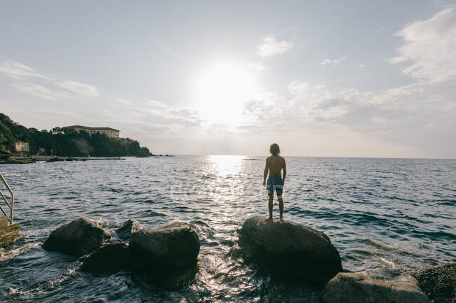 L'uomo in piedi sulla roccia in mare — Foto stock