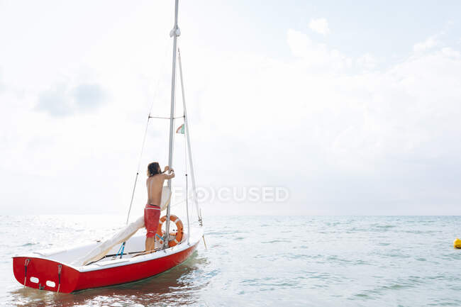Чоловік готує вітрильник у морі — стокове фото