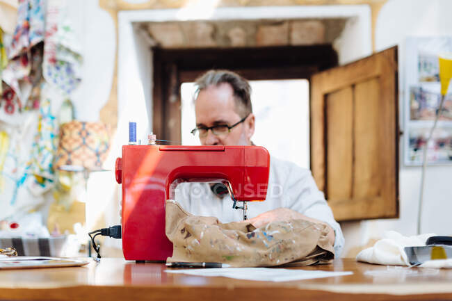 Uomo che utilizza la macchina da cucire in studio creativo — Foto stock