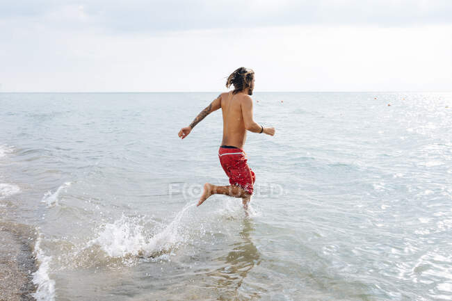 Man running into sea — Stock Photo