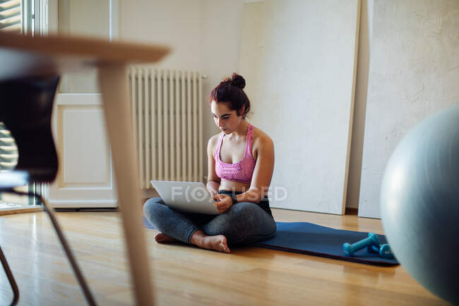 Woman using laptop in exercise clothes — Stock Photo