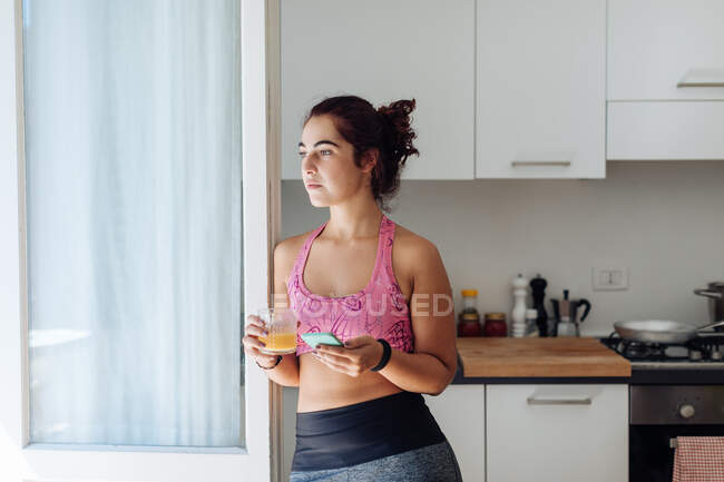 Mujer apoyada contra puerta de la cocina - foto de stock